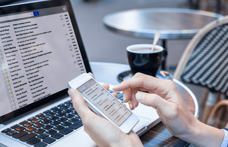 A person scrolling through their email, with their laptop on the table